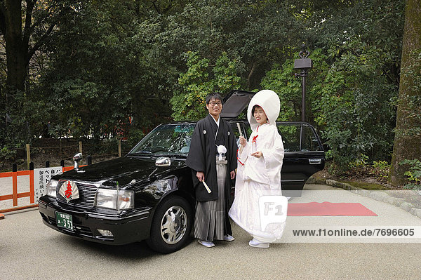 Japanese couple in kimonos  with bridal hood and kimono with brocade  standing in front of the wedding car with a red carpet  Shimogamo Jinja  Kyoto  Japan  East Asia