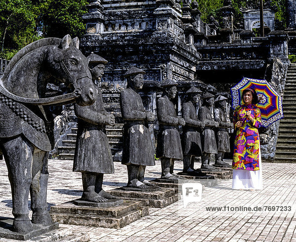 Khai Dinh Tomb  Mandarin soldiers made of stone  young woman wearing a colourful traditional costume
