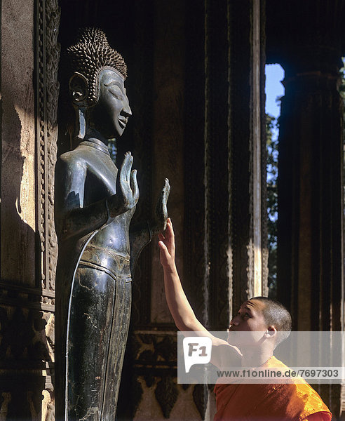 Mönch berührt Buddha-Statue  Altar des Smaragd-Buddha  Wat Ho Prakeo  Ho Phra Keo Tempel  Nationalmuseum