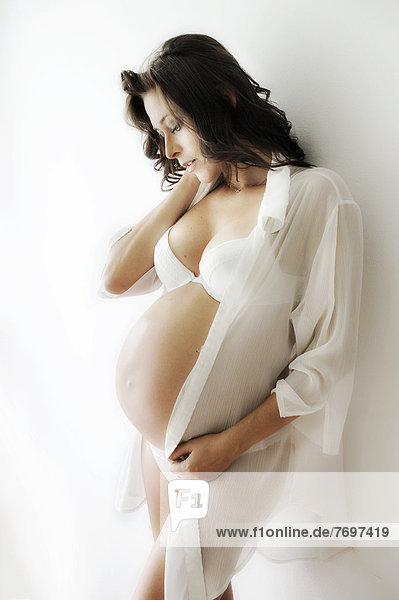 Schwangere Frau mit Schwangerschaftsbauch in Unterwäsche und Bluse