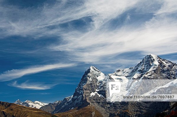 The mountain range of the Bernese Alps with the Eiger summit under a dramatic sky with cirrus clouds Bernese Oberland Switzerland