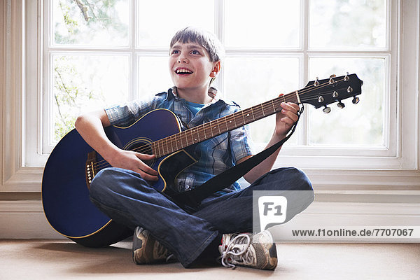 Boy playing guitar on floor