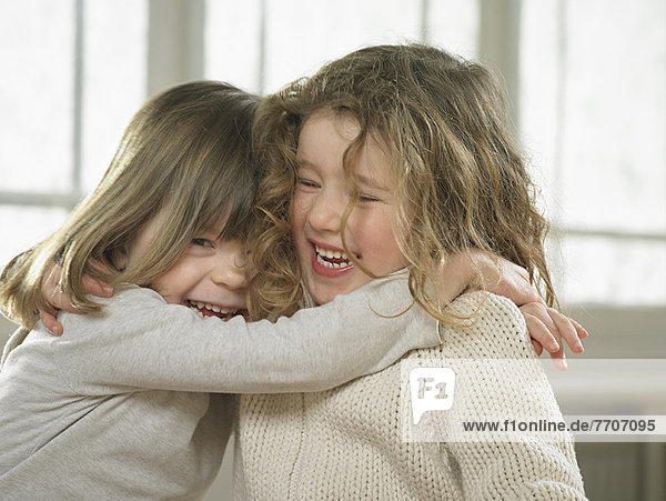 Smiling girls hugging indoors