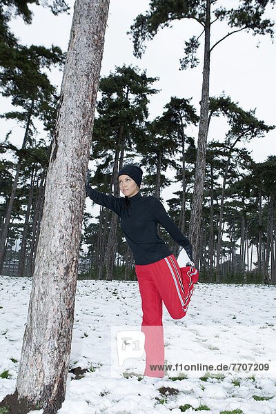 Runner stretching in snowy forest