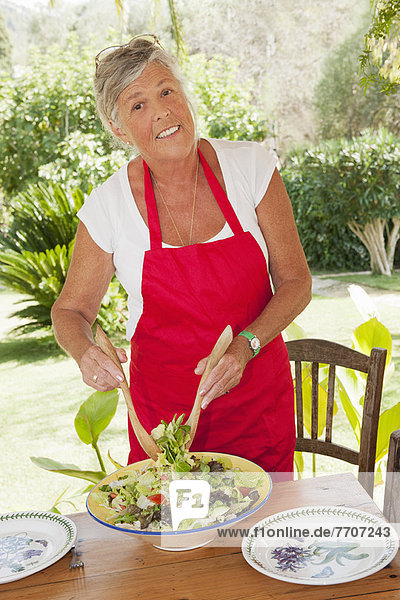 Older woman tossing salad outdoors