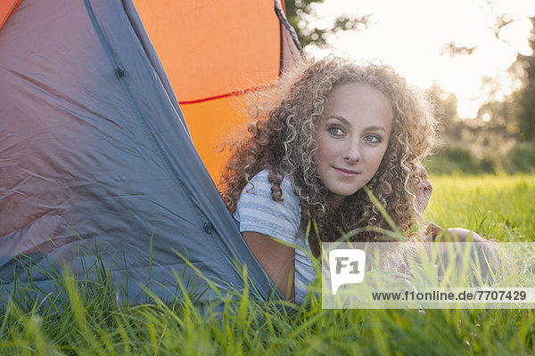 Teenage girl laying in tent at campsite