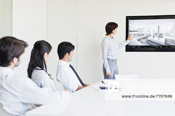 Businesswoman showing image to colleagues