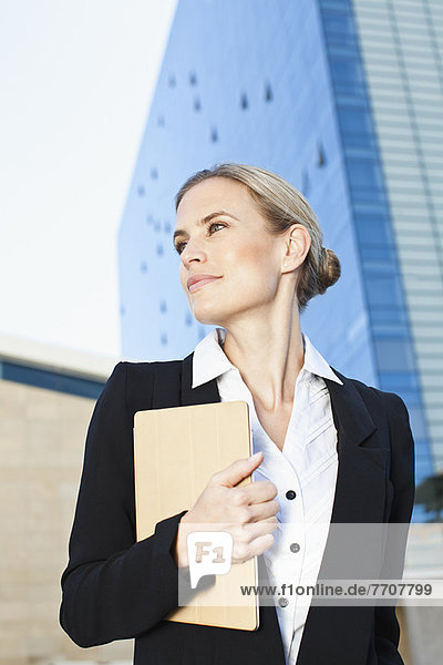 Businesswoman carrying folder outdoors