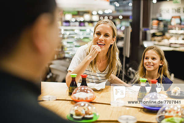 Mutter und Tochter beim Essen im Feinkostladen