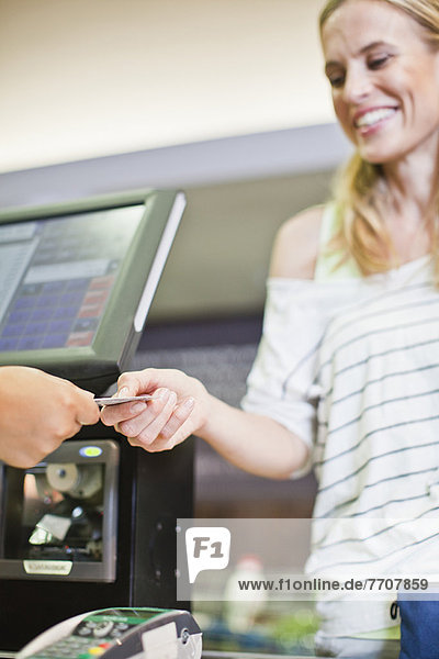 Frau bezahlt mit Kreditkarte im Geschäft