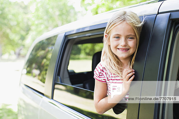 Lächelndes Mädchen im Autofenster stehend