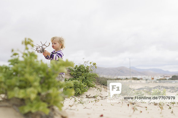 Girl playing with twigs on beach