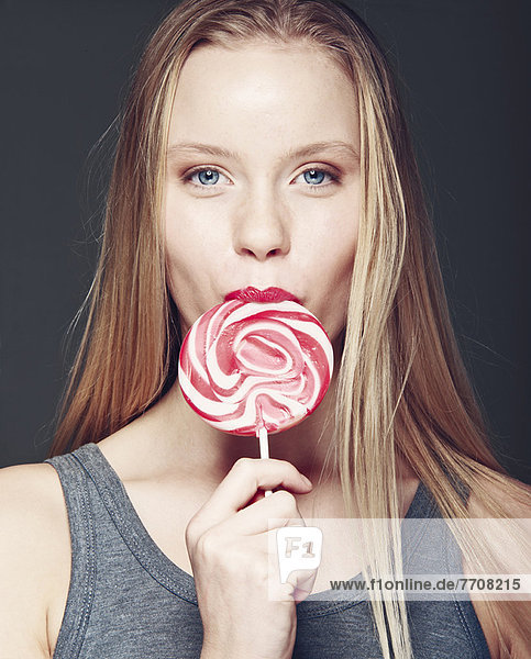 Smiling woman eating lollipop