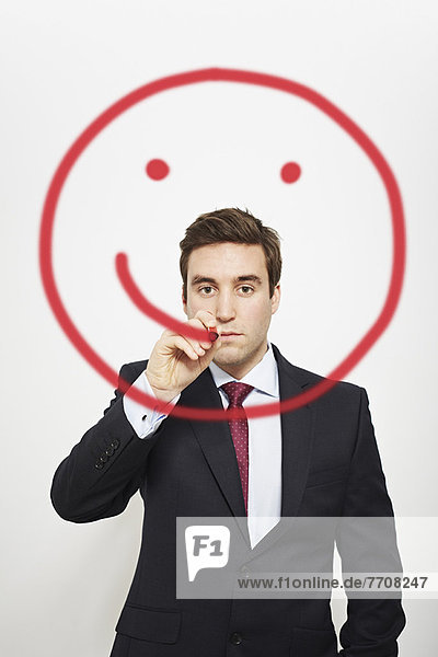 Geschäftsmann zeichnet Smiley-Gesicht in der Luft