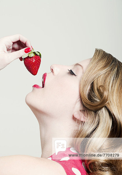 Woman eating strawberry indoors
