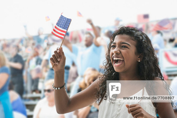 Mädchen jubelnd und mit amerikanischer Flagge winkend