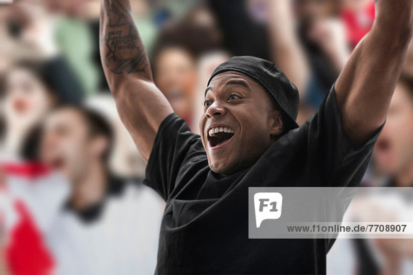 Man at sports game with arms raised