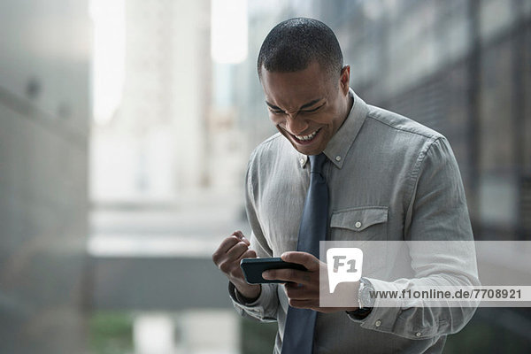 Happy businessman looking at smartphone