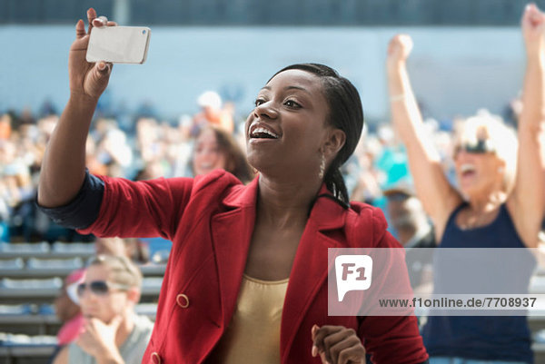Woman in stadium  recording event with her phone
