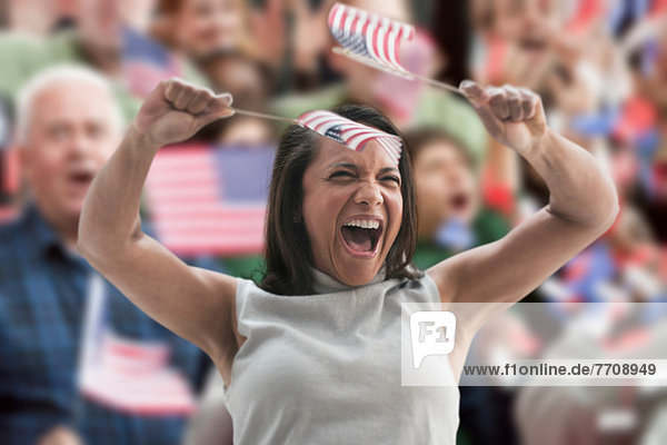 Excited woman waving american flags at rally