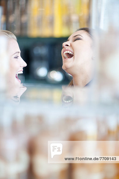 Frauen lachen gemeinsam im Geschäft