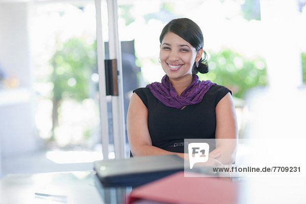 Lächelnde Geschäftsfrau am Schreibtisch sitzend