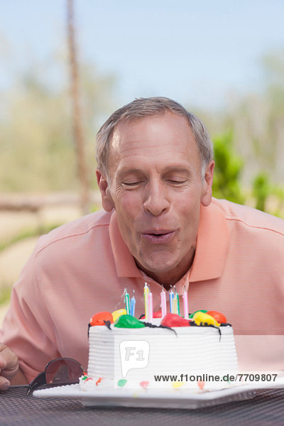 Älterer Mann beim Blasen von Geburtstagskerzen