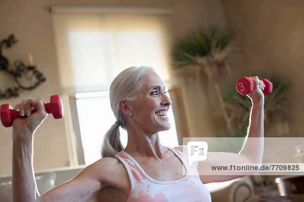 Ältere Frau beim Heben von Gewichten zu Hause