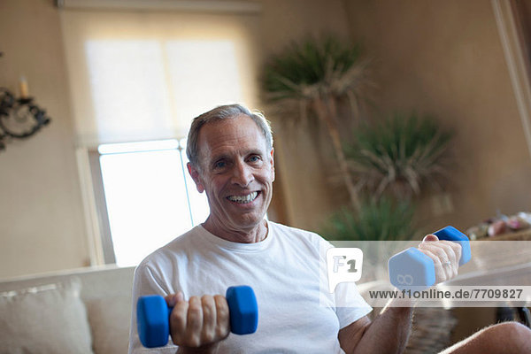 Older man lifting weights at home