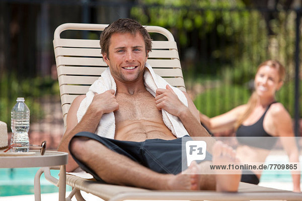 Mann entspannt im Liegestuhl am Pool