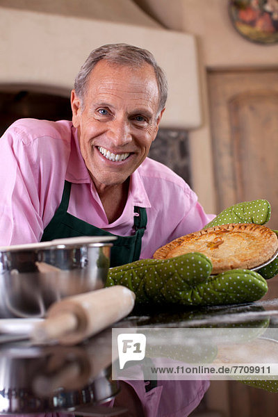 Older man holding pie in kitchen