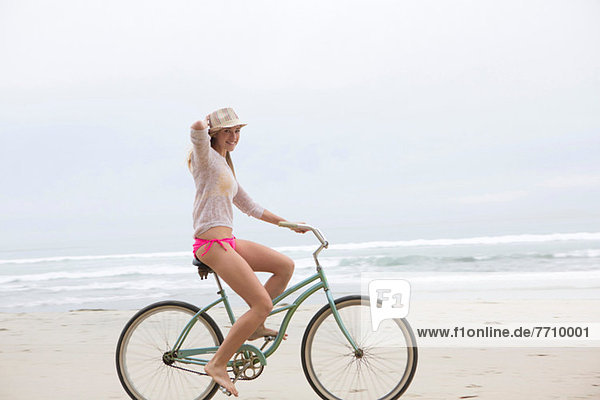 Frau beim Radfahren am Strand