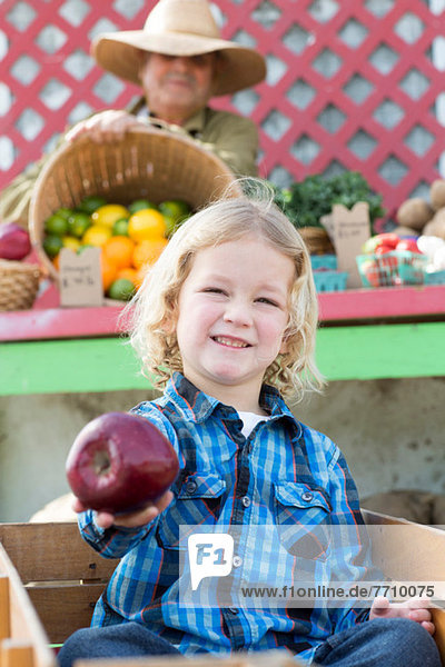 Junge mit Apfel auf dem Bauernmarkt