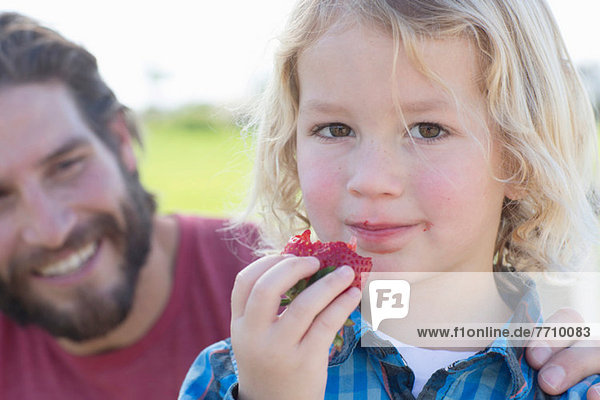 Boy eating strawberry outdoors