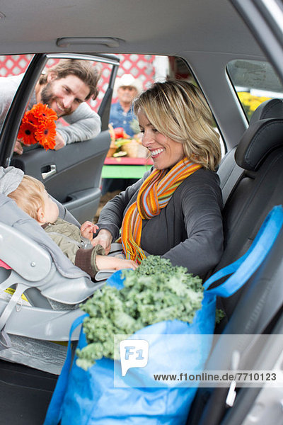 Woman buckling son in car seat