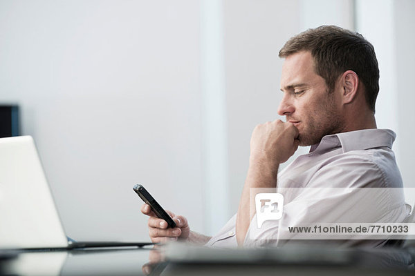 Businessman using cell phone at desk