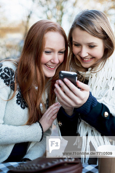 Frauen  die gemeinsam ein Handy benutzen