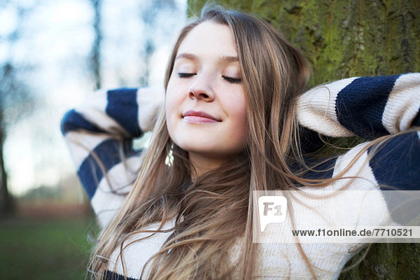 Woman sitting by tree outdoors