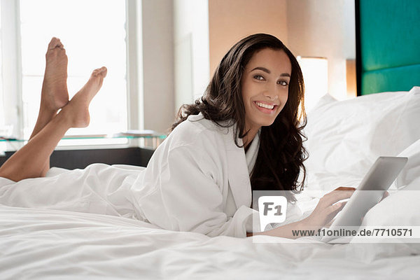 Woman in bathrobe using tablet computer