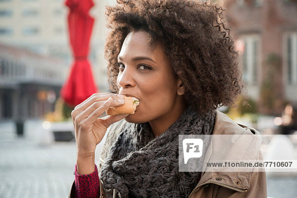 Frau isst auf der Straße in der Stadt