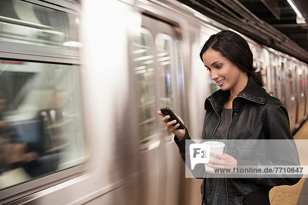 Woman using cell phone at subway station