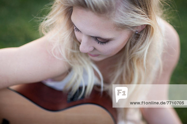 Woman playing guitar in grass