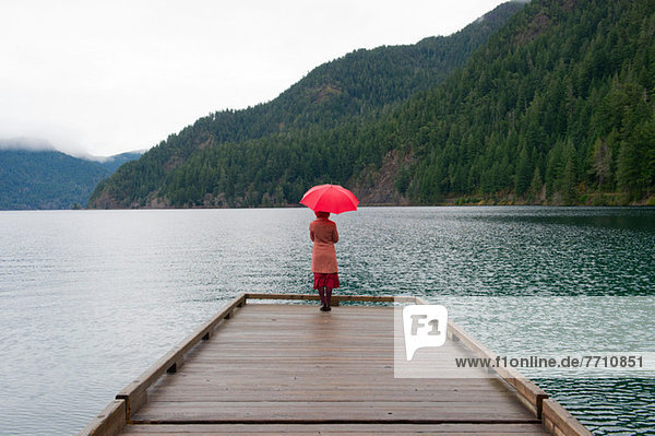 Frau mit Regenschirm auf Holzpfeiler