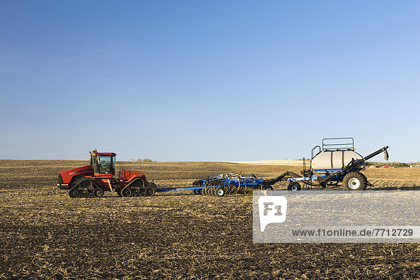 Tractor And Air Seeder In Stubble Field With Blue Sky  Alberta  Canada