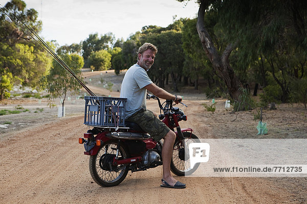 A Man Riding A Motorbike With A Basket On The Back  Dunsborough  West Australia  Australia