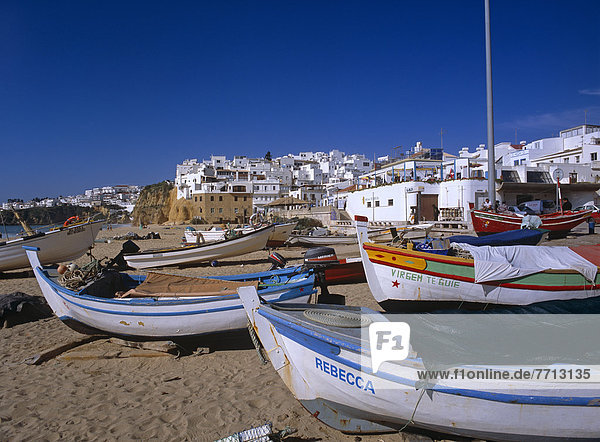 Whitewashed Buildings And Beach With Boats On Sand