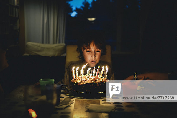 Junge - Person  blasen  bläst  blasend  Dunkelheit  Geburtstag  Kuchen  Kerze  jung