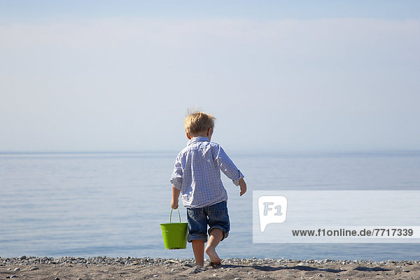 Young boy carrying a pail on the beach by lake ontario Ontario canada