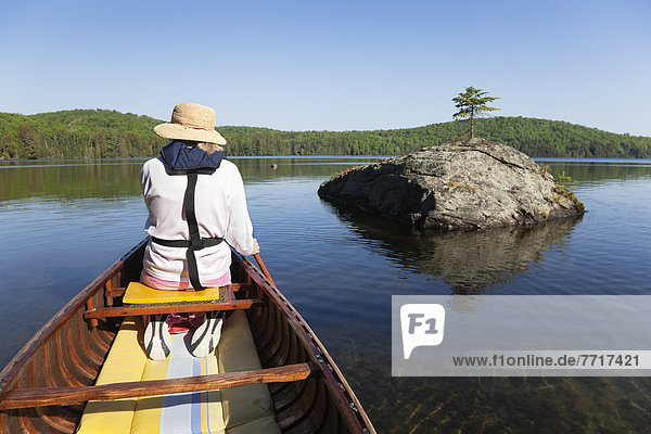 Senior woman paddling her canoe on a sunny morning in algonquin park Ontario canada