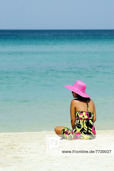 Thailand  Phuket  Kata Noi  Woman In Colorful Dress And Hat Sitting On Tropical Beach.